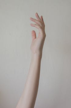 Minimalist photo of an elegant hand gesture with a textured wall backdrop.
