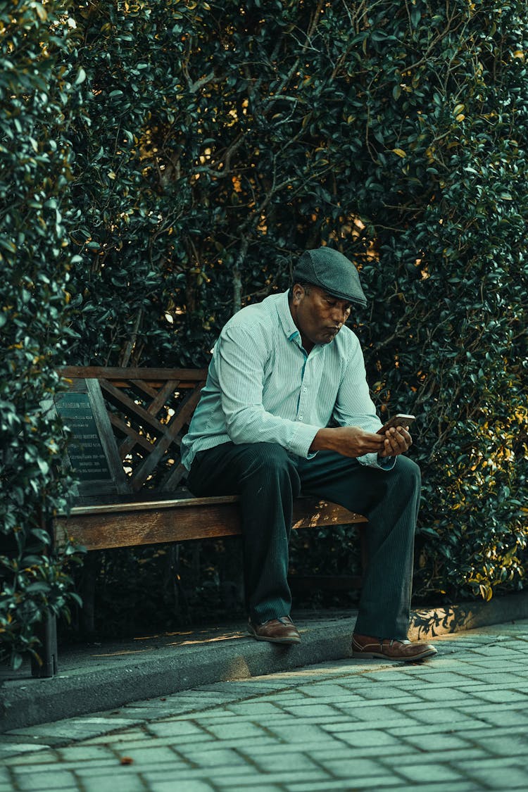 Old Man Sitting On Bench In Park Using Cellphone