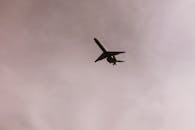 从低角度拍摄，一架飞机在高空飞行的剪影，背景是多云但很小