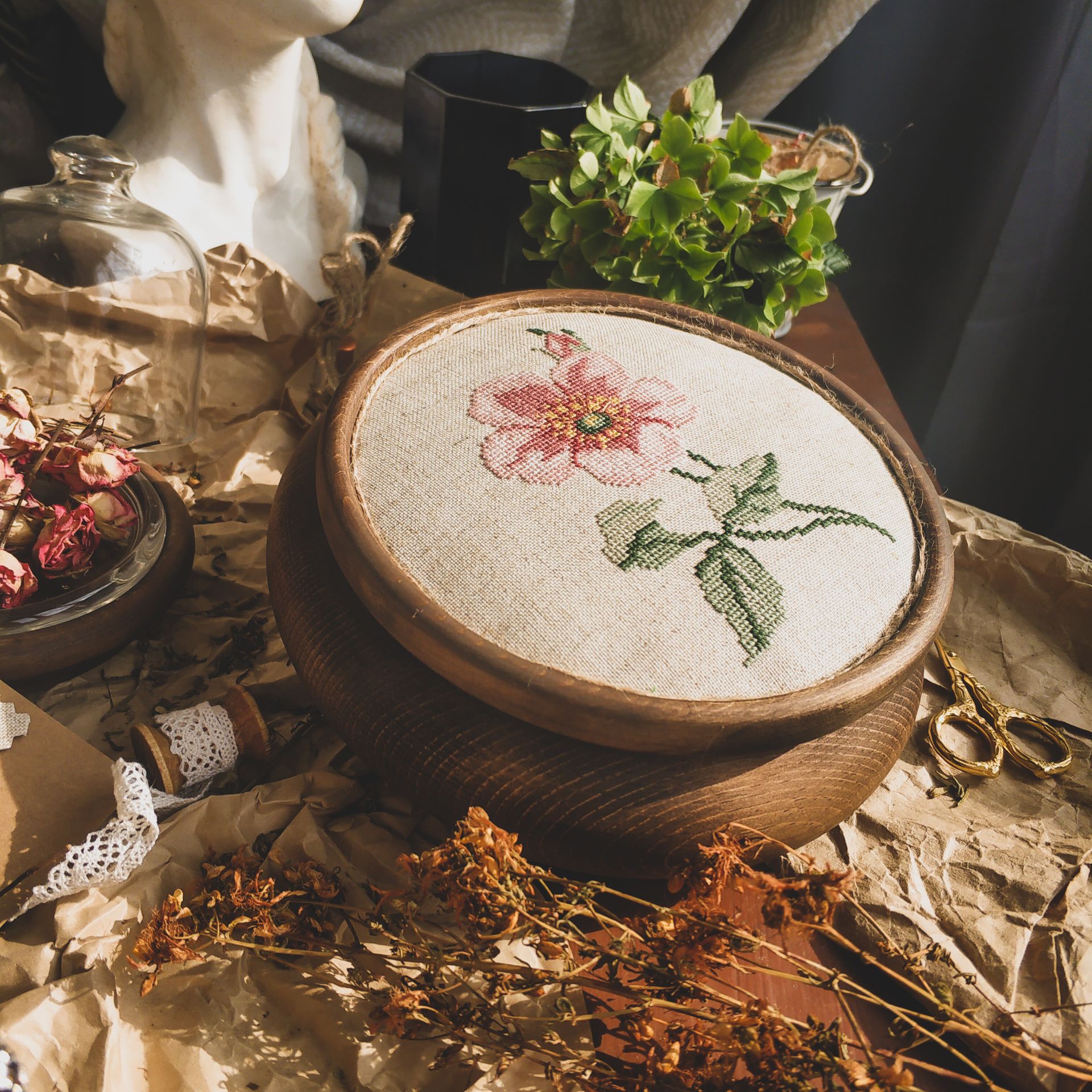 Cross-stitch flower in a wooden hoop among dried flowers