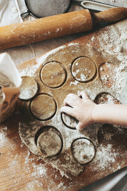 Free Close-up of a hand cutting dough with circular cutters on a floured surface, ready for baking. Stock Photo