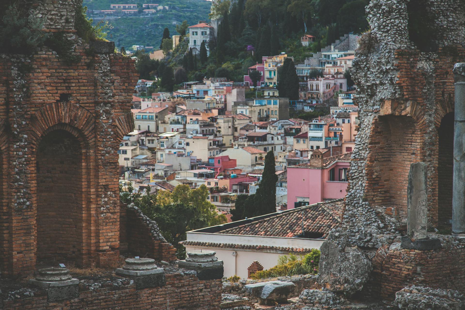 Discover Taormina's ancient ruins overlooking a vibrant Italian townscape.