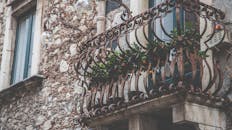 迷人的乡村阳台，配有精致的铁栏杆和新鲜的绿色盆栽