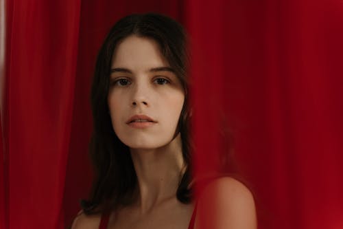 Young Woman Standing Near A Red Curtain