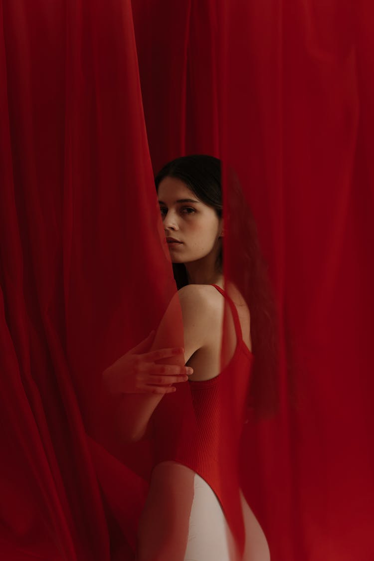 Woman In Red Bathing Suit Standing Behind A Curtain