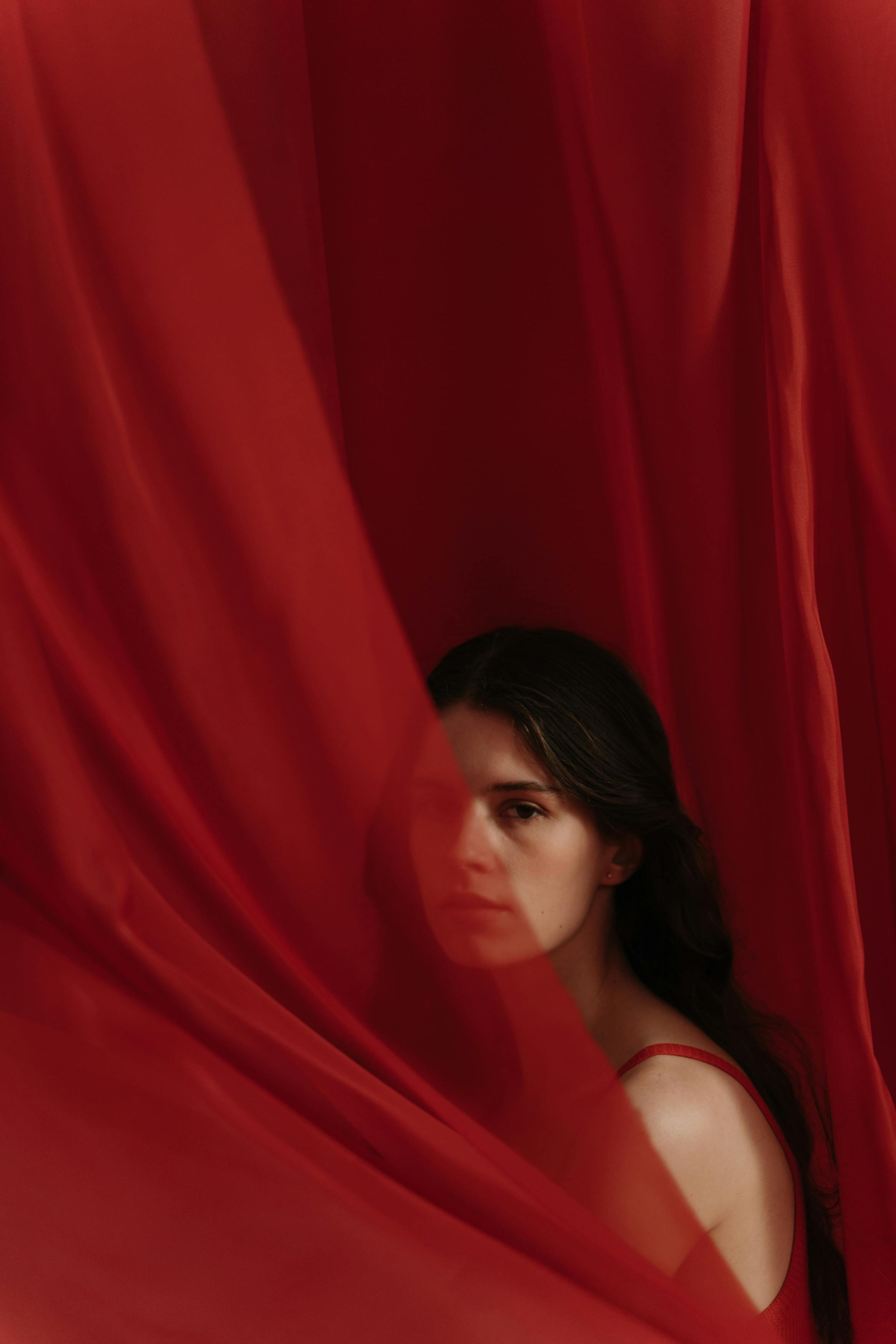 一位部分被流动的红色织物遮盖的女人的艺术肖像