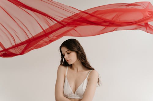 Woman Wearing Bra and Standing under Red Fabric