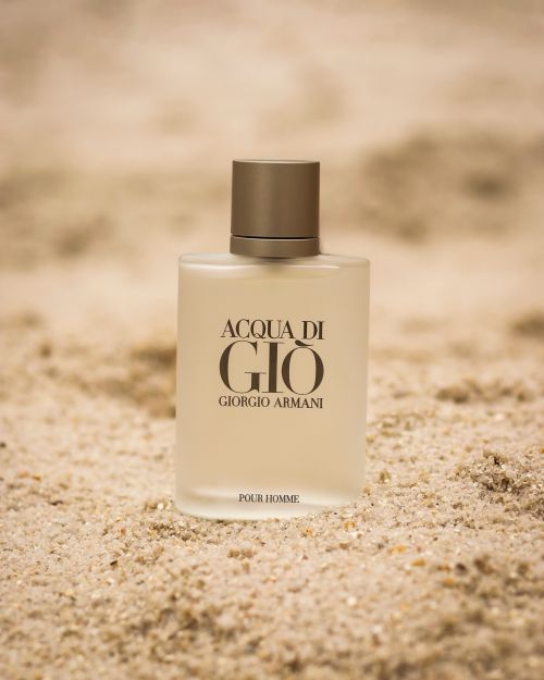Free Close-up of Acqua di Gio Giorgio Armani perfume bottle placed on sand, highlighting luxury fragrance and elegance. Stock Photo