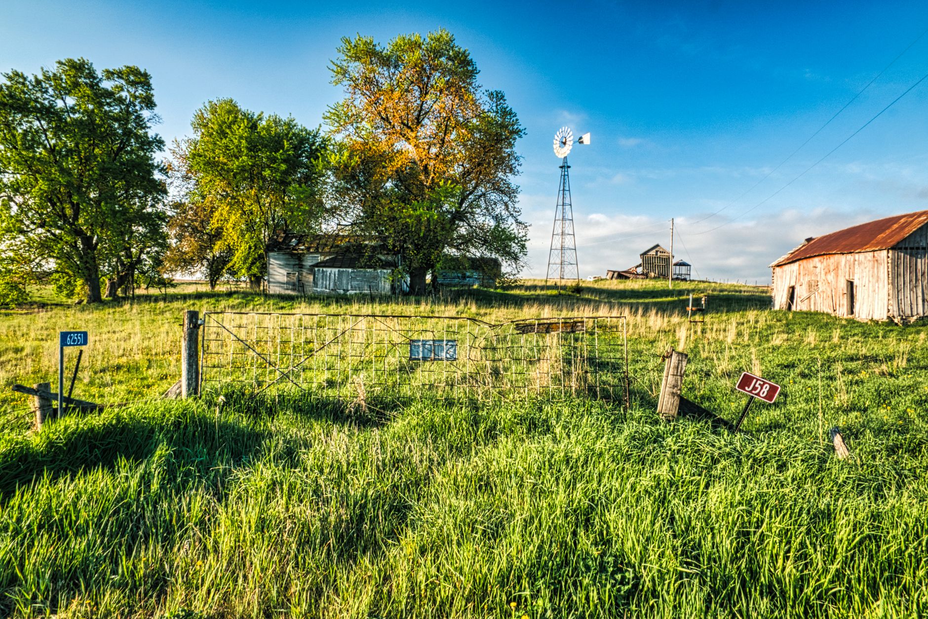 Charming rural farm scene in Minnesota with a windmill and wooden barns under a clear blue sky.