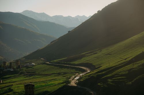 Free A scenic view of a green valley with mountains at sunrise, creating a serene atmosphere. Stock Photo