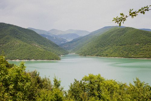 Free Peaceful lake with lush green mountains and clear sky, perfect for nature escape. Stock Photo