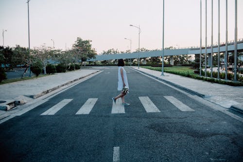 회색과 흰색 도로 횡단 보도에 서있는 여자