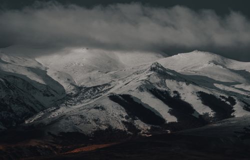 Free A breathtaking view of snow-covered mountains under a cloudy sky with a dramatic atmosphere. Stock Photo