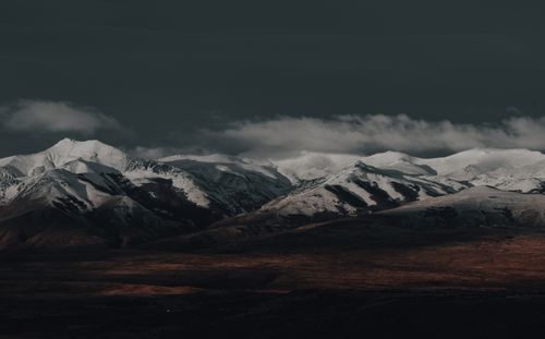 Free Dramatic snow-capped mountain range under a dark sky, offering a serene and majestic view. Stock Photo