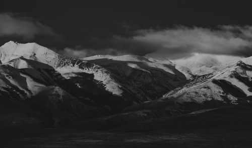Free A striking black and white photograph of snow-covered mountain peaks under a cloudy sky. Stock Photo