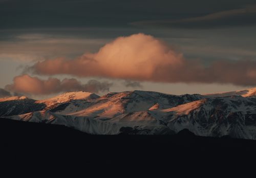 Free Spectacular view of snow-covered mountains under a dramatic sky at sunset, offering a natural scenic beauty. Stock Photo