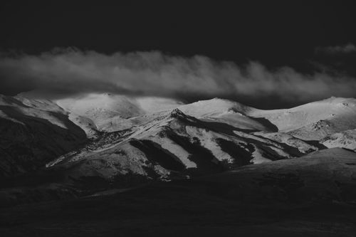 Free Dramatic black and white photo of snow-covered mountains under cloudy skies, capturing winter's essence. Stock Photo