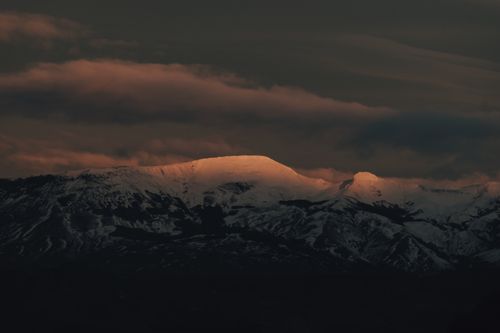 Free A striking view of snow-capped mountains under a moody evening sky. Stock Photo