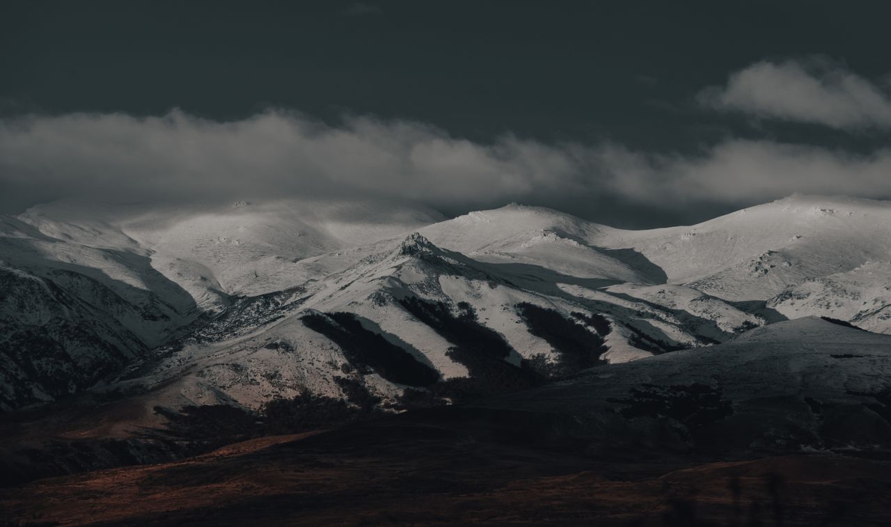 breathtaking view of snow capped mountains under dark clouds perfect f