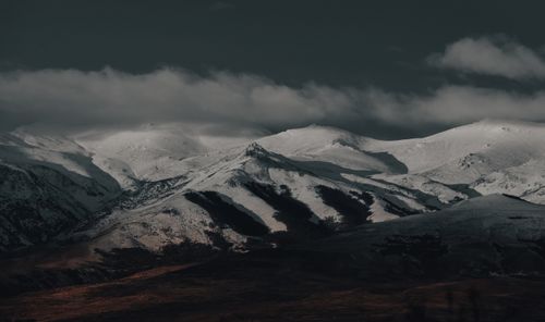 Free Breathtaking view of snow-capped mountains under dark clouds, perfect for nature lovers. Stock Photo