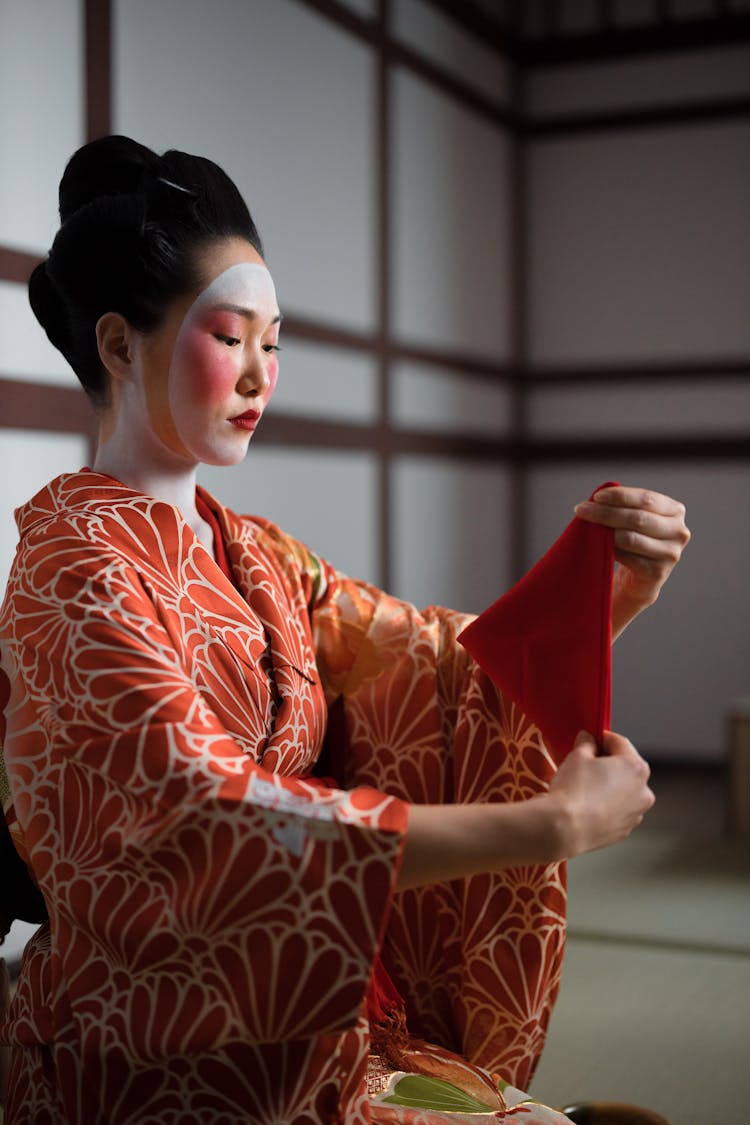 A Woman In Red Kimono Holding A Red Napkin