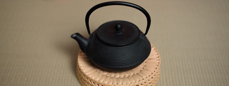 Théière en fonte noire posée sur un sous-tasse en bambou — Tetsubin japonais non émaillé