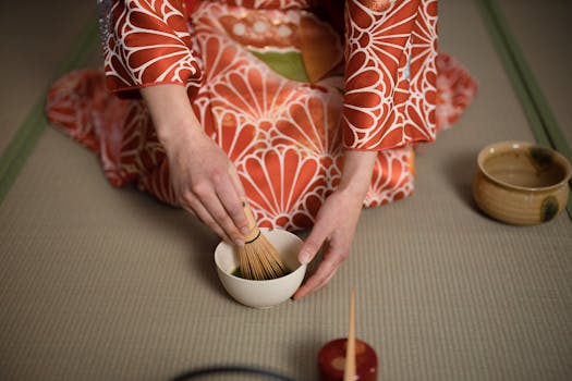 A person in a kimono preparing matcha tea in a traditional ceremony setting.
