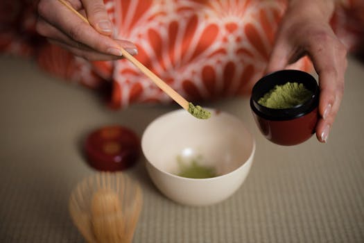Close-up of a woman preparing matcha tea in a traditional Japanese tea ceremony setting.