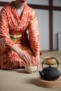 Person in Red and White Floral Long Sleeve Shirt Holding White Ceramic Mug