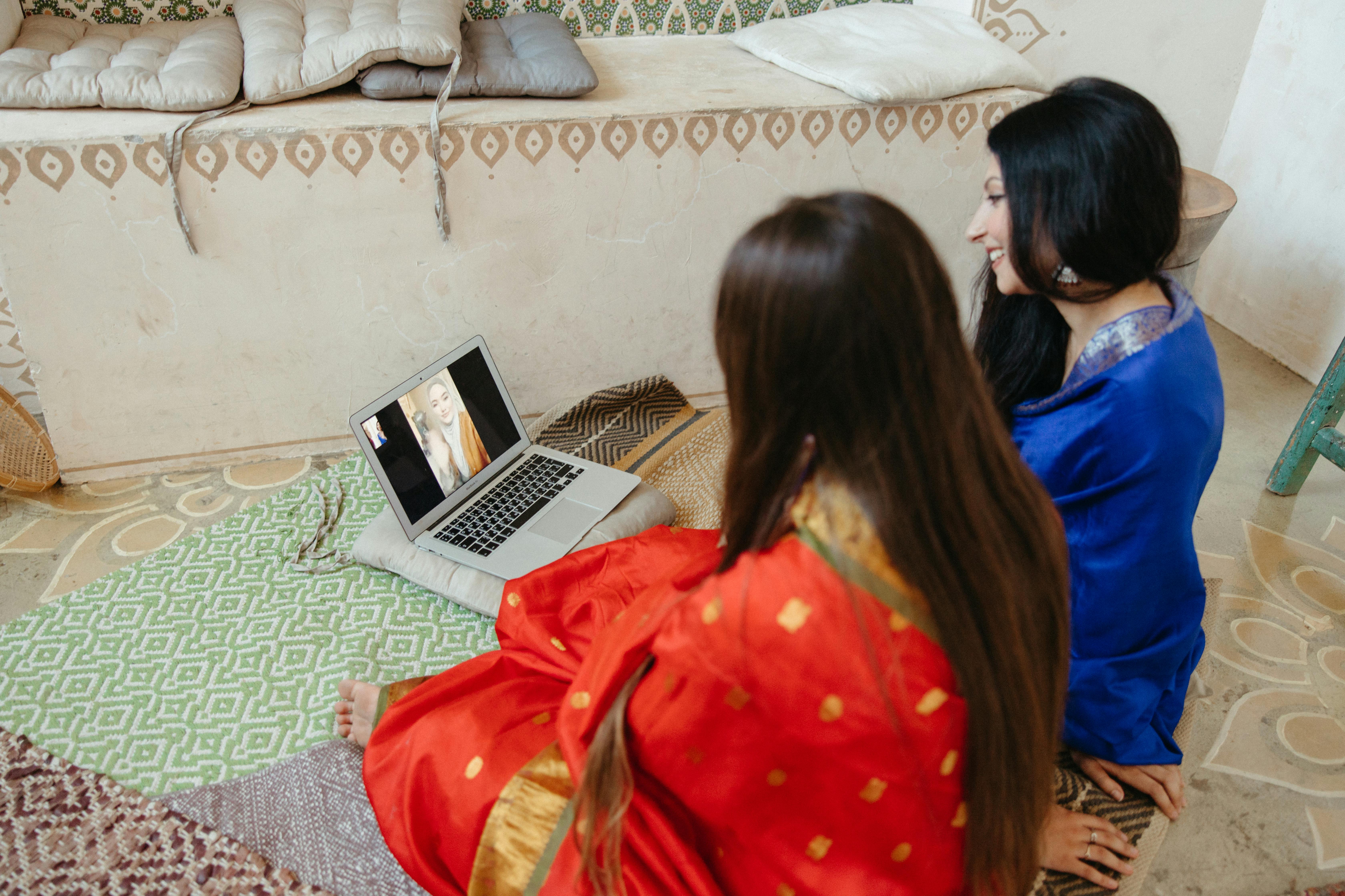 Women participating in a virtual 150 minutes fitness circle for Indian women on a laptop screen, laughing and high-fiving through a video call
