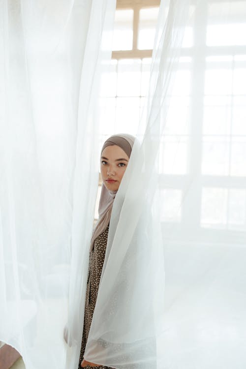 Woman Standing behind the White Curtains