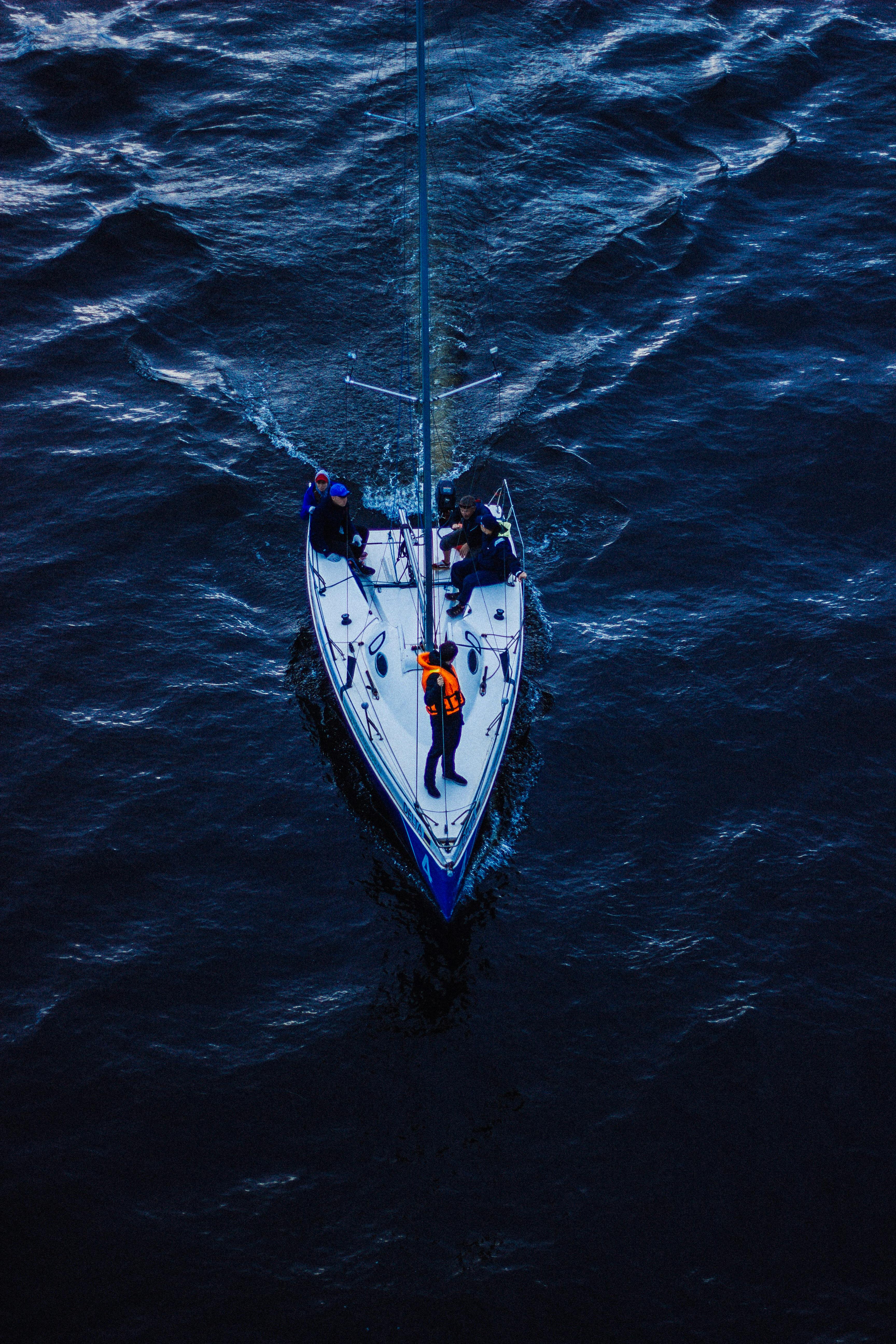 A sailboat with crew sailing on the ocean, captured from above, showcasing marine adventure.