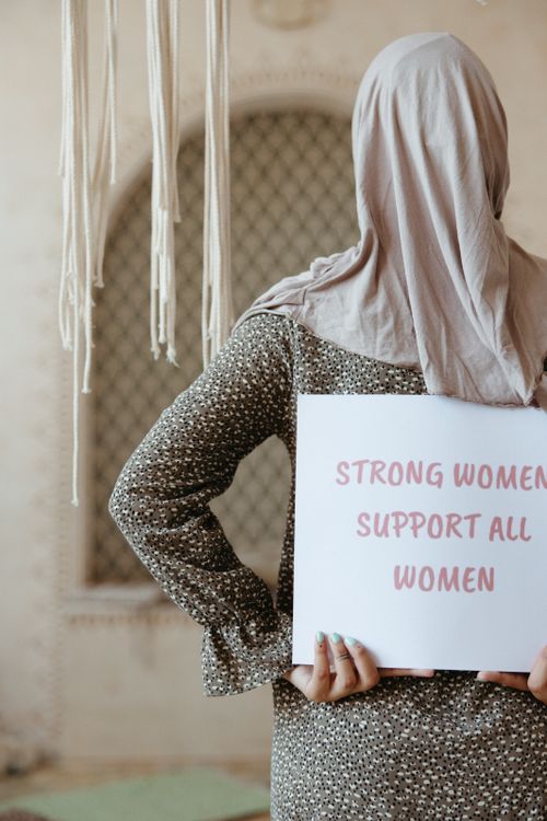 Free A woman in a hijab holds a sign with an empowering message about women's support. Stock Photo