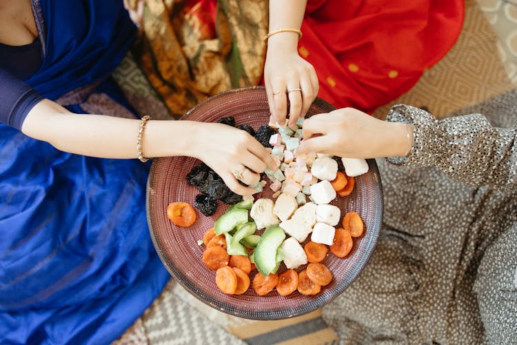 Women Reaching For Snacks In Bowl