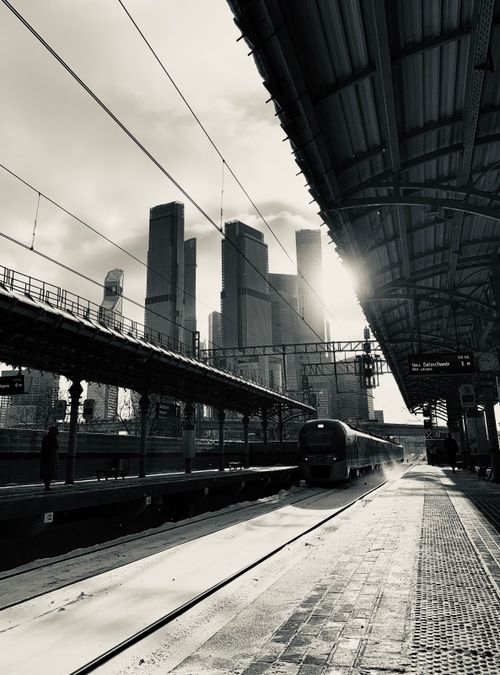 Free Black and white view of a busy urban train station against a city skyline. Stock Photo