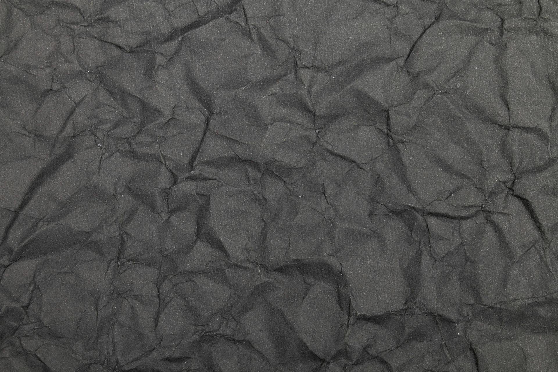 High-resolution close-up of dark, creased paper texture for backgrounds and design works.