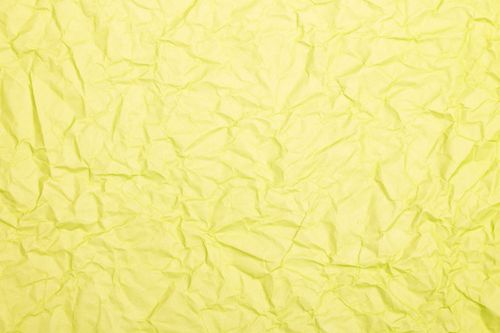 Free Crumpled yellow paper texture background with natural folds and wrinkles. Stock Photo