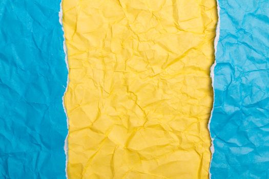 Close-up of a vibrant crumpled paper texture in yellow and blue with copyspace.
