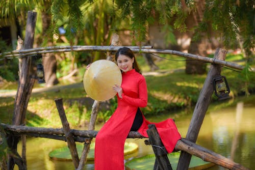 Woman in Red Traditional Wear Holding a Hat