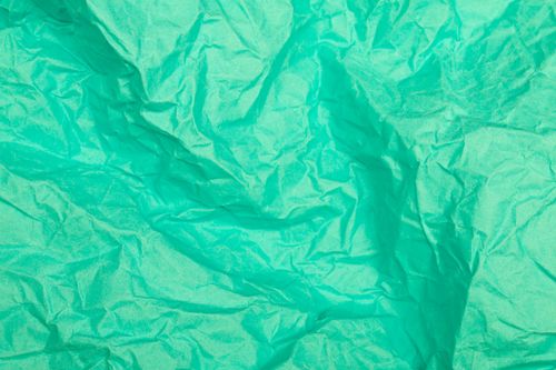 Free A close-up view of a wrinkled green paper texture, perfect for design backgrounds. Stock Photo