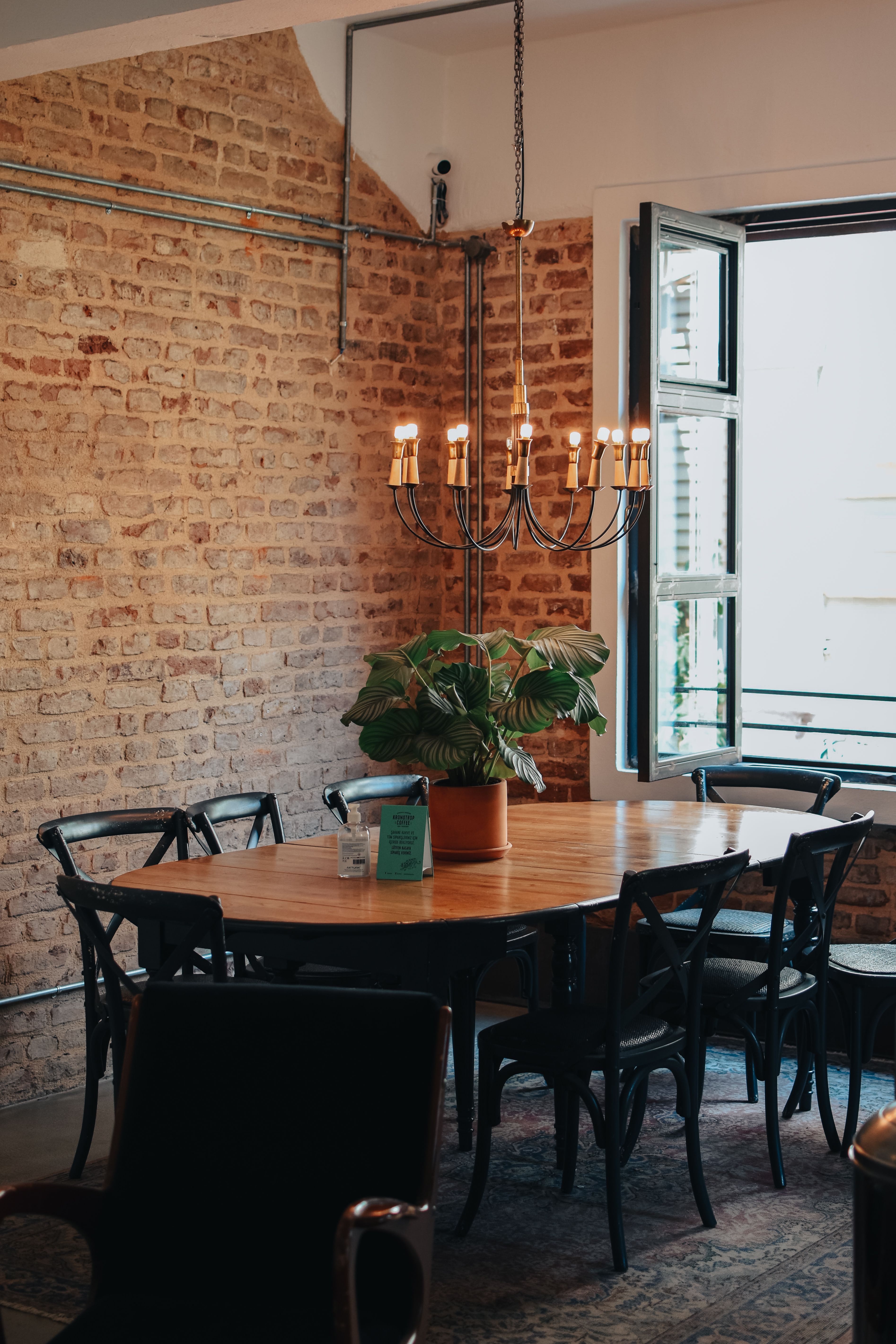 Dining room with rustic brick walls, a round table, and a chandelier