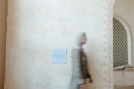 A Woman in Hijab Walking Near the Concrete Wall