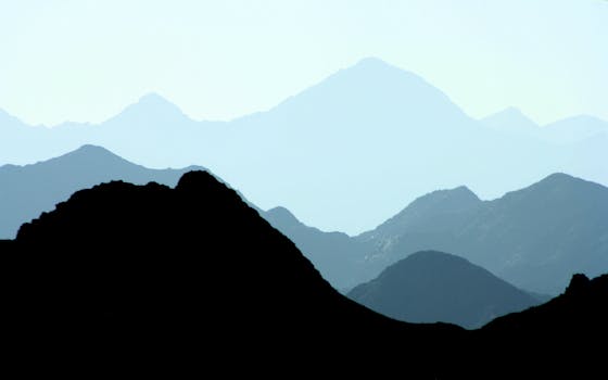 Silhouetted mountain ranges under a clear blue sky, capturing nature's serene beauty.
