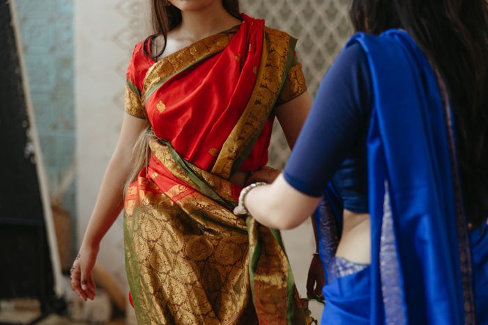 Saree draping being arranged in neat pleats for a bride