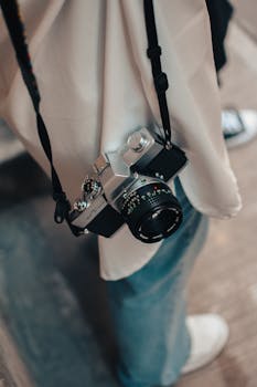 Close-up of a vintage film camera hanging from a person's shoulder, evoking a retro vibe.