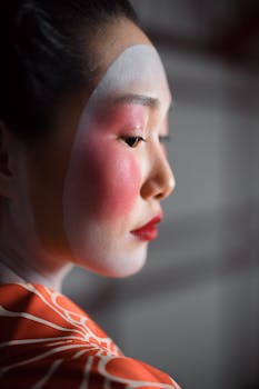 Side view of a geisha with oshiroi makeup and vibrant red lips, showcasing Japanese aesthetics.
