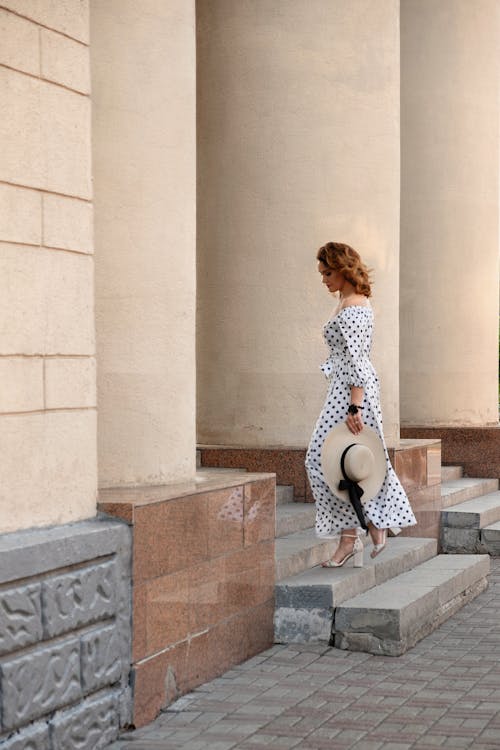 Woman in Polka Dot Dress Sitting on Concrete Stairs