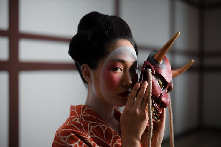 A Geisha Holding A Hannya Mask