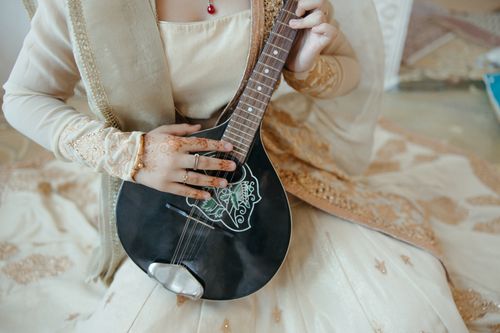 Free A close-up of a woman in ornate ethnic attire playing a mandolin with intricate designs. Stock Photo