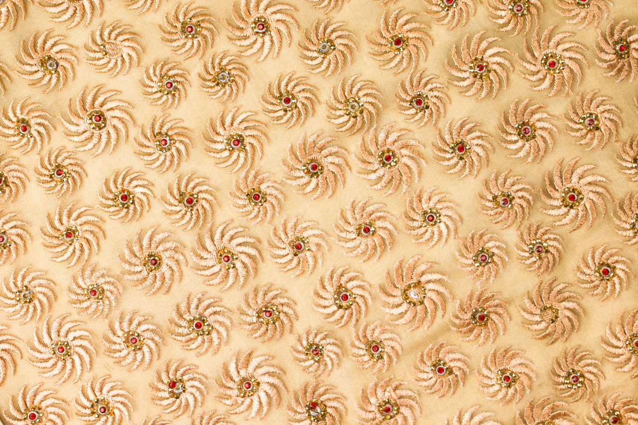 close up of a detailed textile design featuring spiral motifs with bea